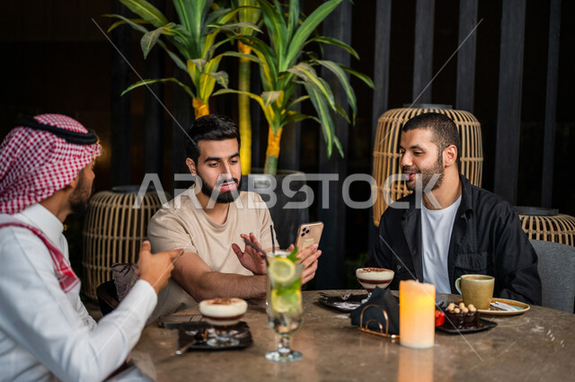 شباب عرب خليجيون سعوديون يجلسون في احد مقاهي المملكة العربية السعودية، استخدام جهاز الهاتف المحمول، تناول القهوة والمشروبات الباردة والحلى اللذيذة، أجواء راقية، أنشطة شبابية ترفيهية، الأجواء الشبابية في المقاهي السعودية