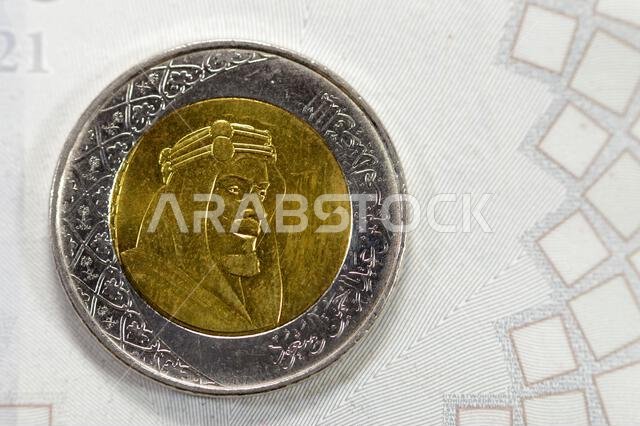 عملة معدنية من فئة ريالين سعوديين، تحمل صورة مؤسس سلالة آل سعود، الملك عبد العزيز، على وجهها الأمامي، بالإضافة إلى شعارات نبالة متعددة.