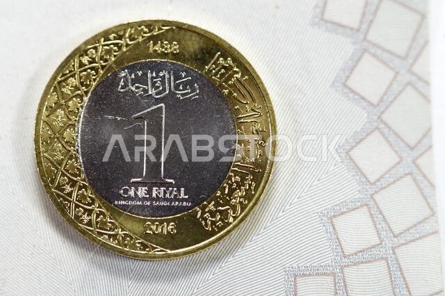One SAR coin Saudi Arabian Riyal features King Salman Bin Abdul Aziz Al Saud on the obverse side, and Multiple Coat of Arms within the Floral Ornament One SAR coin Saudi Arabian Riyal features King Salman Bin Abdul Aziz Al Saud on the obverse side, and Multiple Coat of Arms within the Floral Ornament