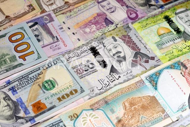 العملات الأمريكية: الدولار الأمريكي والريال السعودي، عملات الريال السعودي بقيم مختلفة، تعكس الوضع الاقتصادي للعملة.