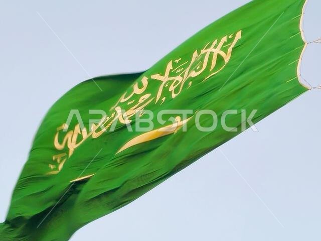 العلم الوطني للمملكة العربية السعودية، خلفية خضراء عليها كتابة عربية وسيف أبيض عليه كتابة للعقيدة الإسلامية، أو