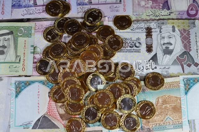 Coins of one Saudi Arabian riyal on Saudi Arabia money banknotes of riyals bills, of different values, money and economic status of the currency, infl