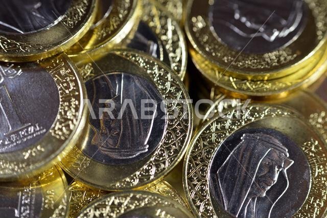 تتميز رزم العملات المعدنية من فئة ريال سعودي واحد بصورة الملك سلمان بن عبد العزيز، مع شعارات النبالة المتعددة داخل الزخارف النباتية، سعود تتميز رزم العملات المعدنية من فئة ريال سعودي واحد بصورة الملك سلمان بن عبد العزيز، مع شعارات النبالة المتعددة داخل الزخارف النباتية، سعود