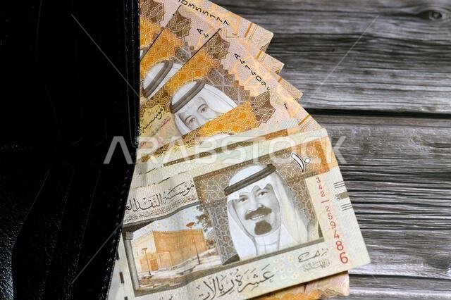 Saudi Arabian Riyals bills banknotes, pile of SAR riyal cash money notes in a black leather wallet, buying, selling, sale, money and economic status,