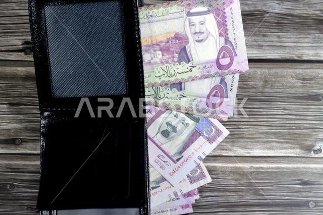 أوراق نقدية من الريال السعودي، رزمة من الأوراق النقدية بالريال السعودي في محفظة جلدية سوداء، شراء، بيع، بيع، المال والوضع الاقتصادي. أوراق نقدية من الريال السعودي، رزمة من الأوراق النقدية بالريال السعودي في محفظة جلدية سوداء، شراء، بيع، بيع، المال والوضع الاقتصادي.