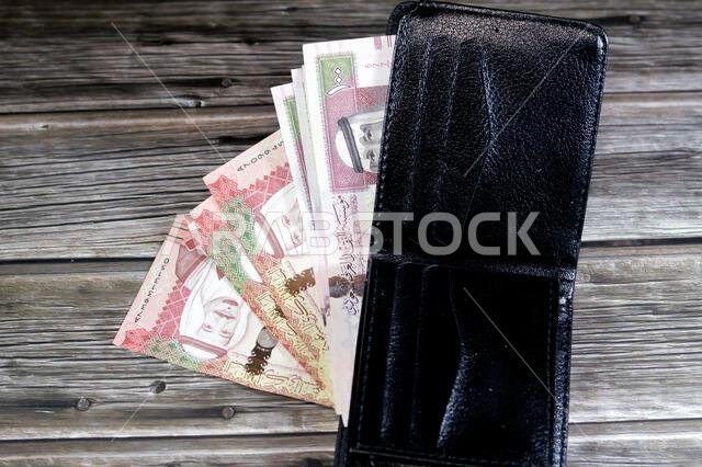 Saudi Arabian Riyals bills banknotes, pile of SAR riyal cash money notes in a black leather wallet, buying, selling, sale, money and economic status,