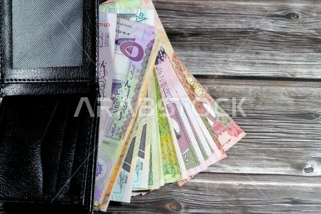 أوراق نقدية من الريال السعودي، رزمة من الأوراق النقدية بالريال السعودي في محفظة جلدية سوداء، شراء، بيع، بيع، المال والوضع الاقتصادي. أوراق نقدية من الريال السعودي، رزمة من الأوراق النقدية بالريال السعودي في محفظة جلدية سوداء، شراء، بيع، بيع، المال والوضع الاقتصادي.