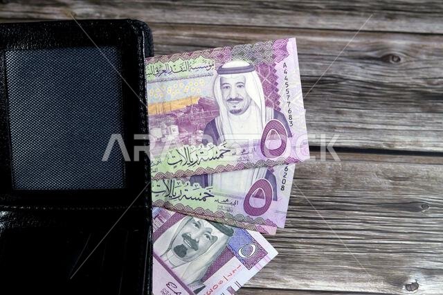 Saudi Arabian Riyals bills banknotes, pile of SAR riyal cash money notes in a black leather wallet, buying, selling, sale, money and economic status,