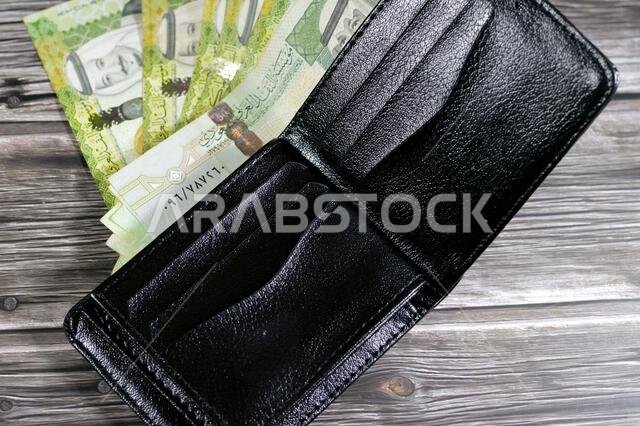 Saudi Arabian Riyals bills banknotes, pile of SAR riyal cash money notes in a black leather wallet, buying, selling, sale, money and economic status, Saudi Arabian Riyals bills banknotes, pile of SAR riyal cash money notes in a black leather wallet, buying, selling, sale, money and economic status,