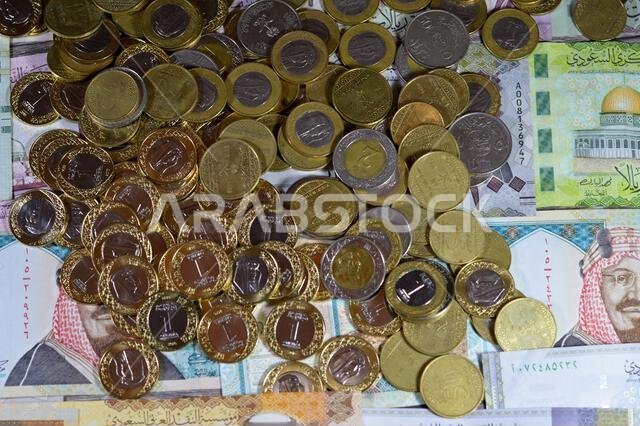 Coins of Saudi Arabian riyal, 2, 1, half and quarter coin on Saudi Arabia money banknotes of riyals bills, of different values, money and economic sta Coins of Saudi Arabian riyal, 2, 1, half and quarter coin on Saudi Arabia money banknotes of riyals bills, of different values, money and economic sta