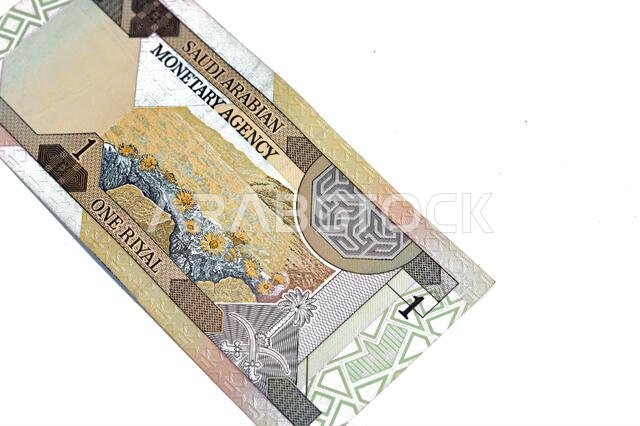 يُظهر الوجه الخلفي لورقة نقدية سعودية قديمة من فئة ريال واحد منظرًا طبيعيًا وشعار المملكة العربية السعودية المتمثل في سيفين أسفله.