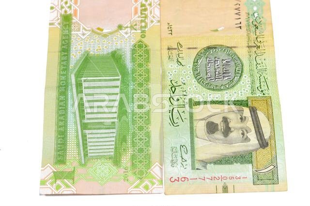 تحمل ورقة نقدية من فئة ريال سعودي واحد صورة الملك عبد الله ومبنى مقر مؤسسة النقد العربي السعودي وشعار النبالة.