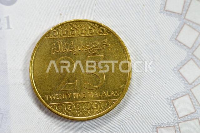 A quarter of SAR Saudi Arabian riyal coin 25 Halalas, features Coat Of Arms Two crossed swords and Palm Tree, Name of King Salman Bin AbdulAziz on the