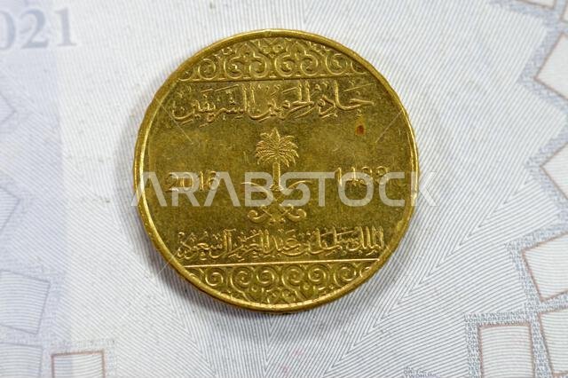 A quarter of SAR Saudi Arabian riyal coin 25 Halalas, features Coat Of Arms Two crossed swords and Palm Tree, Name of King Salman Bin AbdulAziz on the