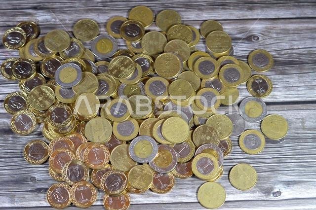 عملات معدنية متنوعة من المملكة العربية السعودية بقيم وأزمنة مختلفة، وعملة الريال السعودي القديمة والجديدة من فئات ريالين، وريال واحد، ونصف ريال، وربع ريال.