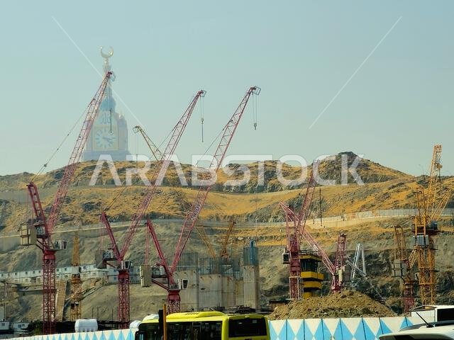 Mecca, Saudi Arabia, June 8 2024: Clock tower building, Cranes of construction site and the mountains of Makkah, Mecca  is the capital of Mecca Provin