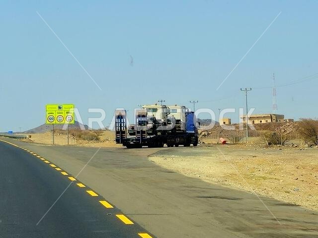 Makkah Madinah road, Saudi Arabia, June 25 2024: A big flatbed truck loaded with a shipment being transferred on a highway with a large lorry, shipmen