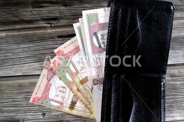 أوراق نقدية من الريال السعودي، رزمة من الأوراق النقدية بالريال السعودي في محفظة جلدية سوداء، شراء، بيع، بيع، المال والوضع الاقتصادي. أوراق نقدية من الريال السعودي، رزمة من الأوراق النقدية بالريال السعودي في محفظة جلدية سوداء، شراء، بيع، بيع، المال والوضع الاقتصادي.