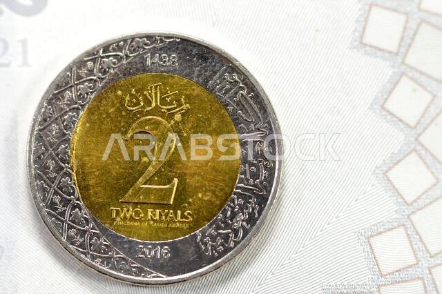 عملة معدنية من فئة ريالين سعوديين، تحمل صورة مؤسس سلالة آل سعود، الملك عبد العزيز، على وجهها الأمامي، بالإضافة إلى شعارات نبالة متعددة.