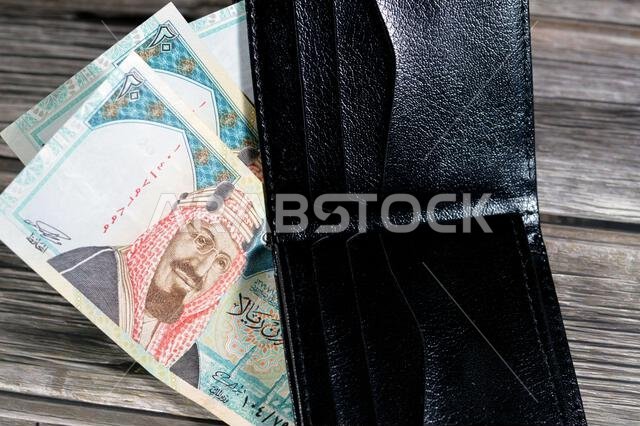 أوراق نقدية من الريال السعودي، رزمة من الأوراق النقدية بالريال السعودي في محفظة جلدية سوداء، شراء، بيع، بيع، المال والوضع الاقتصادي. أوراق نقدية من الريال السعودي، رزمة من الأوراق النقدية بالريال السعودي في محفظة جلدية سوداء، شراء، بيع، بيع، المال والوضع الاقتصادي.