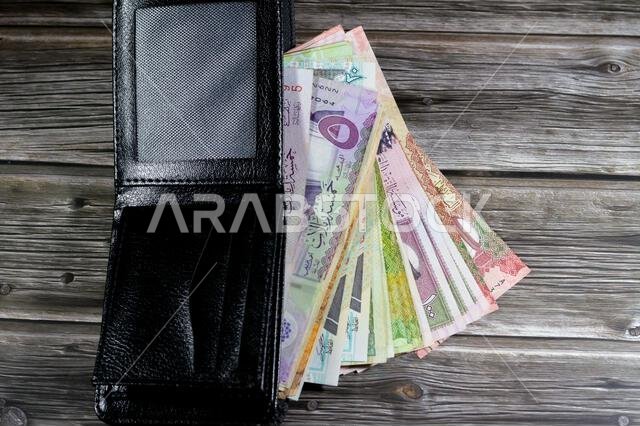 Saudi Arabian Riyals bills banknotes, pile of SAR riyal cash money notes in a black leather wallet, buying, selling, sale, money and economic status,