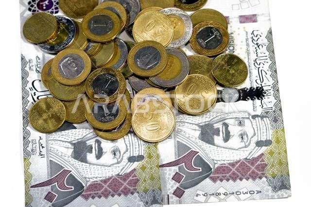 ورقة نقدية من فئة 200 ريال سعودي، تحمل صورة الملك عبد العزيز آل سعود ورؤية المملكة العربية السعودية لعام 2030، بالإضافة إلى عملات معدنية سعودية من فئة ريالين.