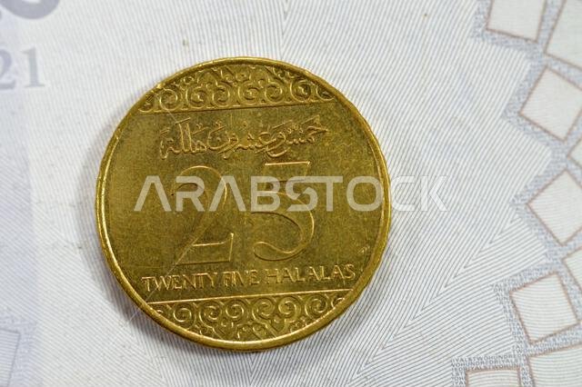 ربع ريال سعودي، عملة معدنية من فئة 25 هللة، تحمل شعار النبالة وسيفين متقاطعين وشجرة نخيل، واسم الملك سلمان بن عبد العزيز عليها.