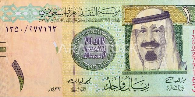 جزء كبير من وجه ورقة نقدية من فئة ريال سعودي واحد (1 ريال سعودي) يحمل صورة الملك عبد الله بن عبد العزيز، وأول عملة إسلامية قديمة.