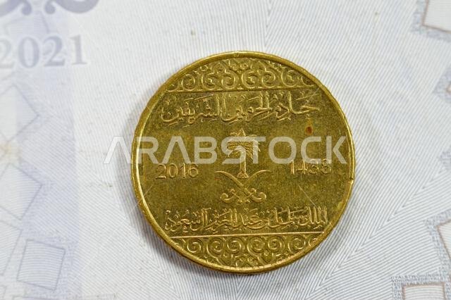 A quarter of SAR Saudi Arabian riyal coin 25 Halalas, features Coat Of Arms Two crossed swords and Palm Tree, Name of King Salman Bin AbdulAziz on the