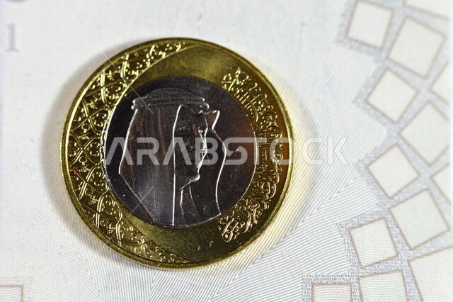 One SAR coin Saudi Arabian Riyal features King Salman Bin Abdul Aziz Al Saud on the obverse side, and Multiple Coat of Arms within the Floral Ornament