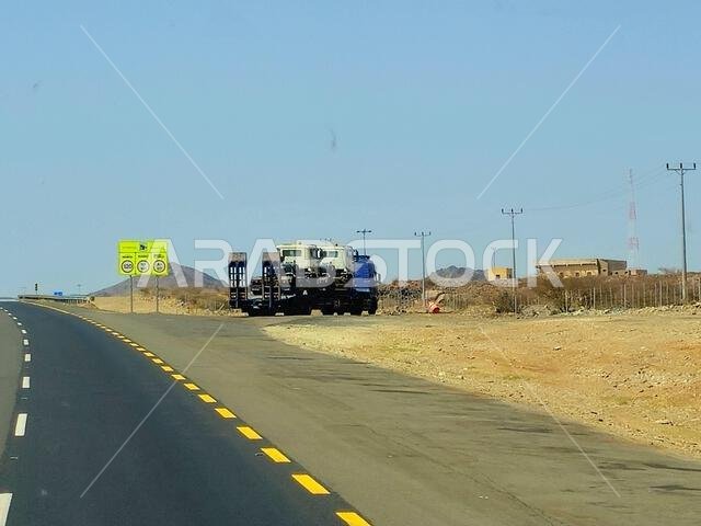 Makkah Madinah road, Saudi Arabia, June 25 2024: A big flatbed truck loaded with a shipment being transferred on a highway with a large lorry, shipmen