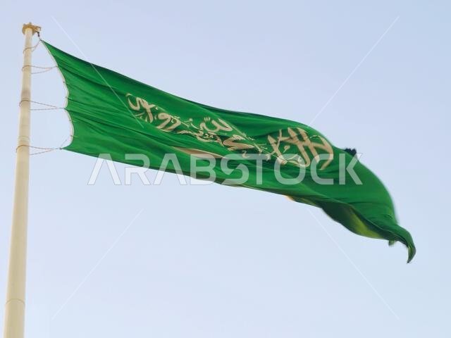 العلم الوطني للمملكة العربية السعودية، خلفية خضراء عليها كتابة عربية وسيف أبيض عليه كتابة للعقيدة الإسلامية، أو