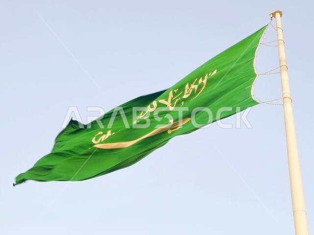 العلم الوطني للمملكة العربية السعودية، خلفية خضراء عليها كتابة عربية وسيف أبيض عليه كتابة للعقيدة الإسلامية، أو