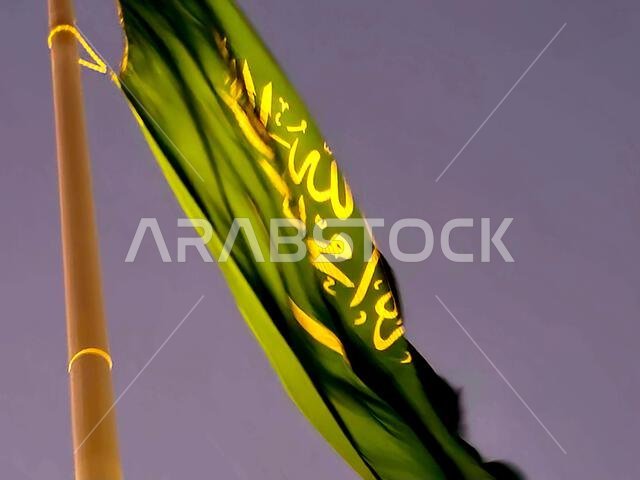 The national flag of Saudi Arabia kingdom, a green background with Arabic inscription and a sword in white, with inscription of the Islamic creed, or