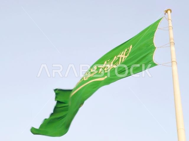 العلم الوطني للمملكة العربية السعودية، خلفية خضراء عليها كتابة عربية وسيف أبيض عليه كتابة للعقيدة الإسلامية، أو