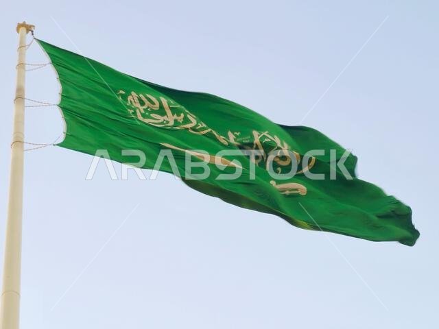 العلم الوطني للمملكة العربية السعودية، خلفية خضراء عليها كتابة عربية وسيف أبيض عليه كتابة للعقيدة الإسلامية، أو