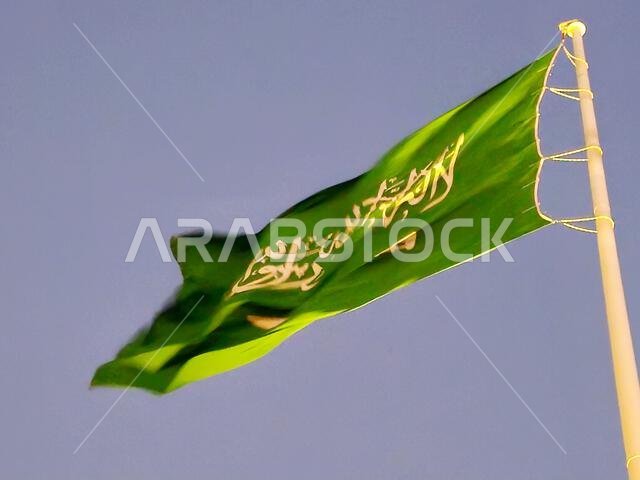 العلم الوطني للمملكة العربية السعودية، خلفية خضراء عليها كتابة عربية وسيف أبيض عليه كتابة للعقيدة الإسلامية، أو