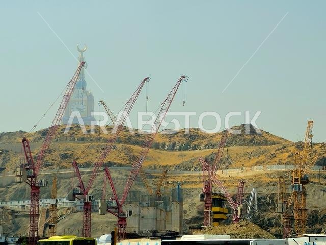 Mecca, Saudi Arabia, June 8 2024: Clock tower building, Cranes of construction site and the mountains of Makkah, Mecca  is the capital of Mecca Provin
