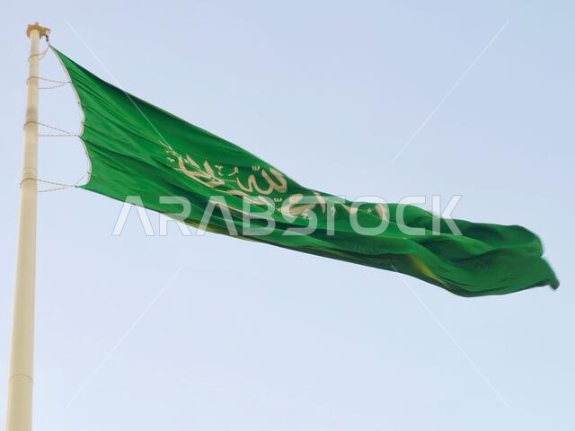 العلم الوطني للمملكة العربية السعودية، خلفية خضراء عليها كتابة عربية وسيف أبيض عليه كتابة للعقيدة الإسلامية، أو