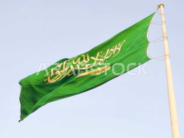 The national flag of Saudi Arabia kingdom, a green background with Arabic inscription and a sword in white, with inscription of the Islamic creed, or