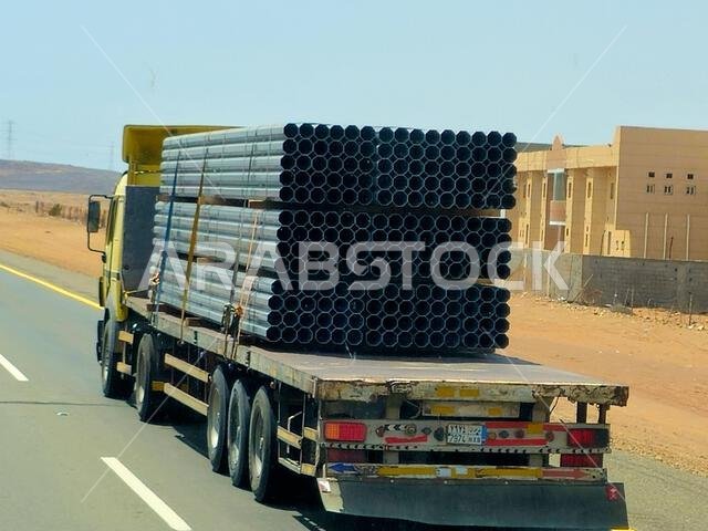 طريق مكة المكرمة - المدينة المنورة، المملكة العربية السعودية، 25 يونيو 2024: شاحنة مسطحة كبيرة محملة بشحنة تُنقل على طريق سريع بواسطة شاحنة نقل كبيرة وبحارة.