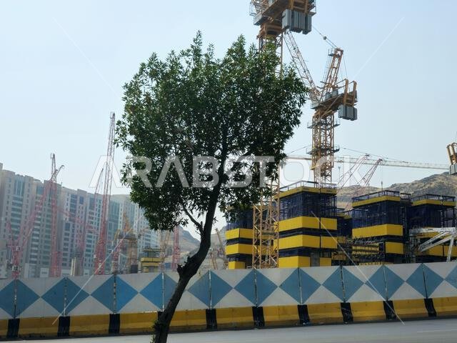 Mecca, Saudi Arabia, June 8 2024: Cranes of a construction site of a new high rise and the mountains of Makkah, Mecca is the capital of Mecca Provinc Mecca, Saudi Arabia, June 8 2024: Cranes of a construction site of a new high rise and the mountains of Makkah, Mecca is the capital of Mecca Provinc