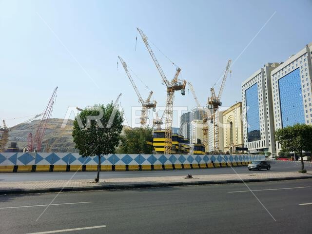 Mecca, Saudi Arabia, June 8 2024: Cranes of a construction site of a new high rise and the mountains of Makkah, Mecca  is the capital of Mecca Provinc