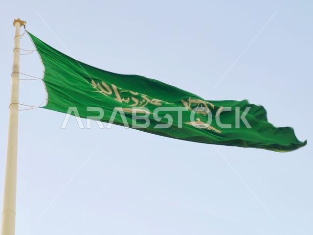 العلم الوطني للمملكة العربية السعودية، خلفية خضراء عليها كتابة عربية وسيف أبيض عليه كتابة للعقيدة الإسلامية، أو