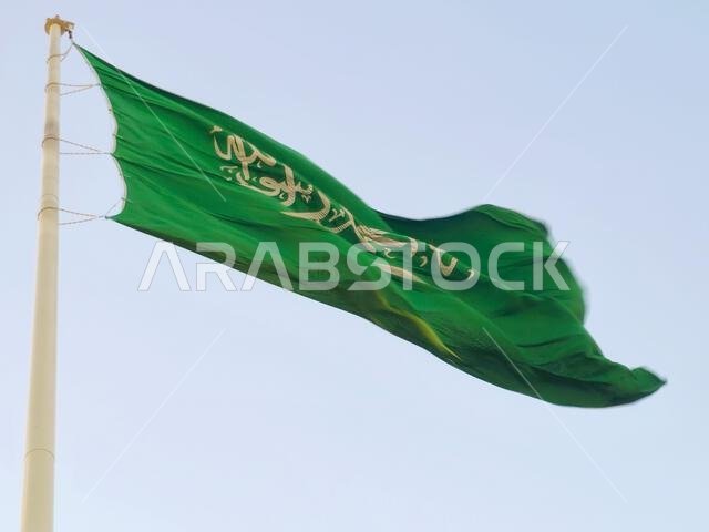 The national flag of Saudi Arabia kingdom, a green background with Arabic inscription and a sword in white, with inscription of the Islamic creed, or