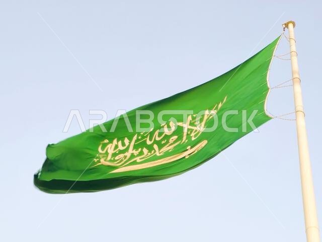 The national flag of Saudi Arabia kingdom, a green background with Arabic inscription and a sword in white, with inscription of the Islamic creed, or
