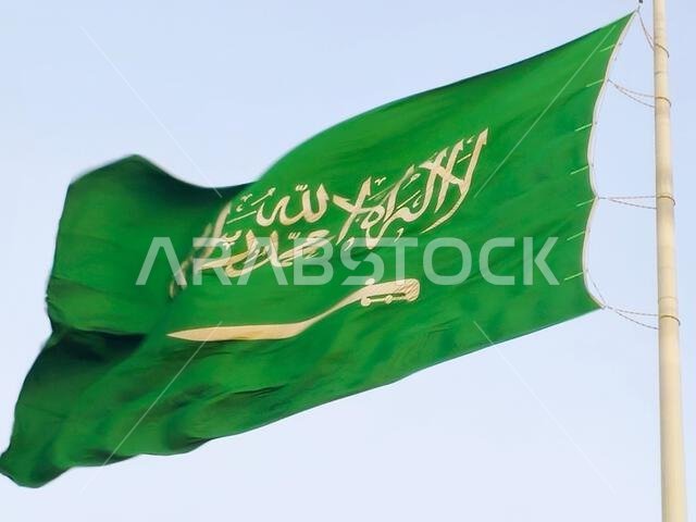 العلم الوطني للمملكة العربية السعودية، خلفية خضراء عليها كتابة عربية وسيف أبيض عليه كتابة للعقيدة الإسلامية، أو