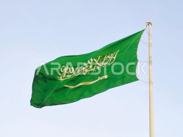 العلم الوطني للمملكة العربية السعودية، خلفية خضراء عليها كتابة عربية وسيف أبيض عليه كتابة للعقيدة الإسلامية، أو