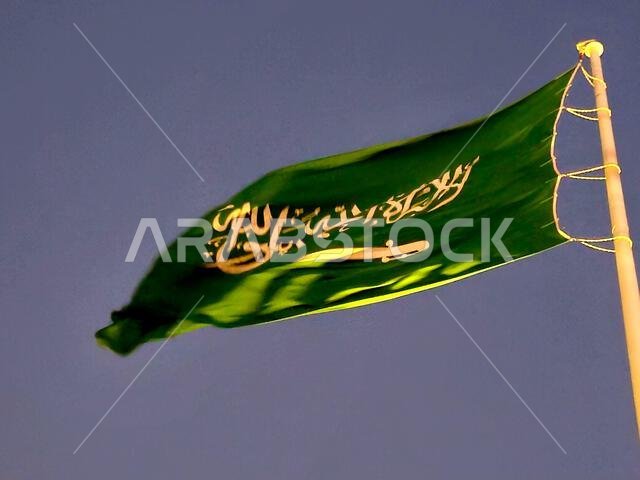 العلم الوطني للمملكة العربية السعودية، خلفية خضراء عليها كتابة عربية وسيف أبيض عليه كتابة للعقيدة الإسلامية، أو