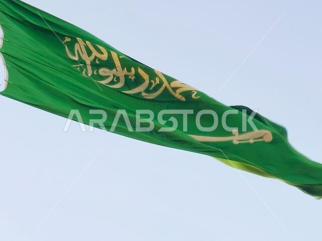 العلم الوطني للمملكة العربية السعودية، خلفية خضراء عليها كتابة عربية وسيف أبيض عليه نقش للعقيدة الإسلامية، أو
